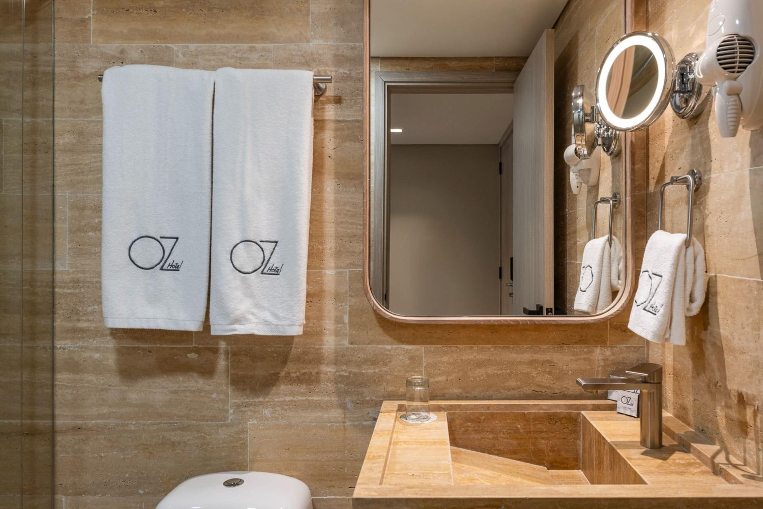A modern bathroom with two towels hanging on a towel rack, a large mirror, and a sink with a vanity.