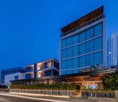 Un hotel moderno con un llamativo letrero que dice '07 Hotel', que presenta una estructura de varios pisos con grandes ventanales y un área de entrada cubierta.