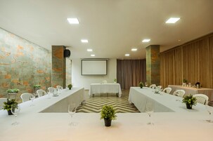 Una sala de conferencias con una larga mesa, sillas y una pantalla para proyector.