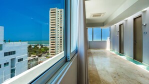 A hotel corridor with a view of a tall building and a beach. - Hotel OZ Grand (Cartagena)