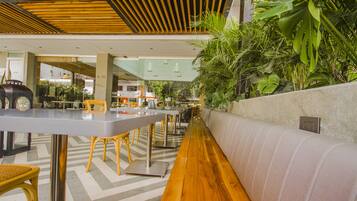 Un comedor moderno en interior con suelo de madera, mesas de metal y sillas amarillas.