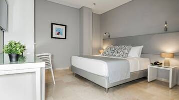 A modern bedroom with a bed, bedside tables, a desk, and a chair.