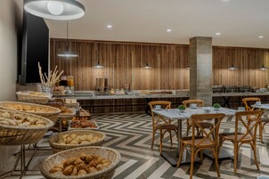 Un restaurante moderno con una barra alargada, cestas de mimbre con pan y sillas de madera.
