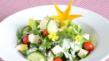 Un plato blanco con ensalada sobre un mantel a cuadros rojo y blanco.