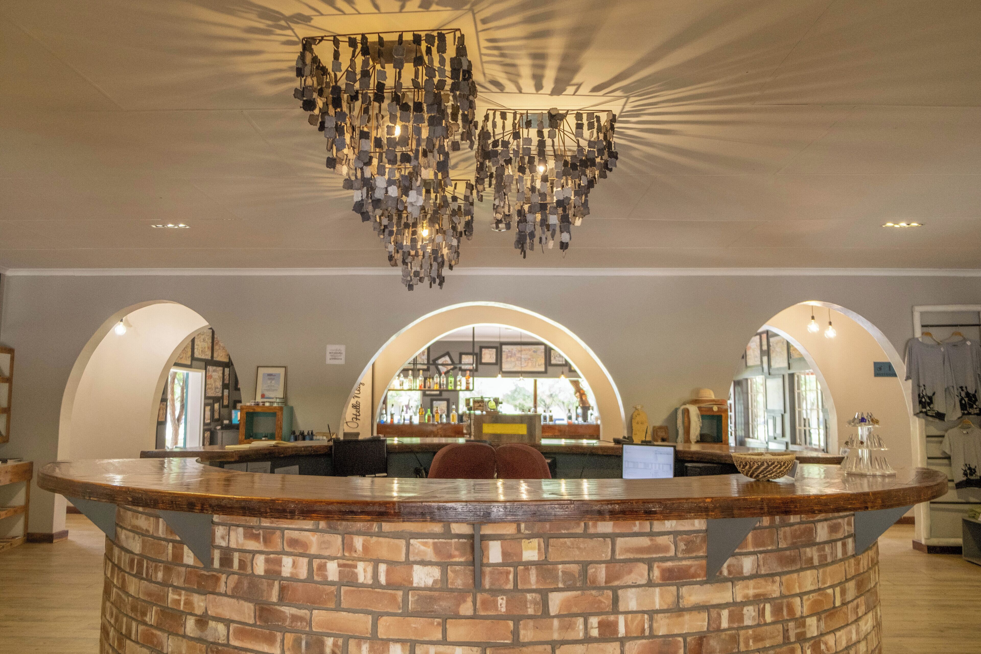 A bar area with a brick counter, arched doorways, and a hanging chandelier.