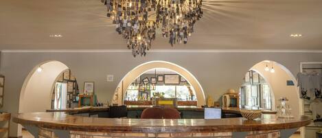 A bar area with a brick counter, arched doorways, and a hanging chandelier.