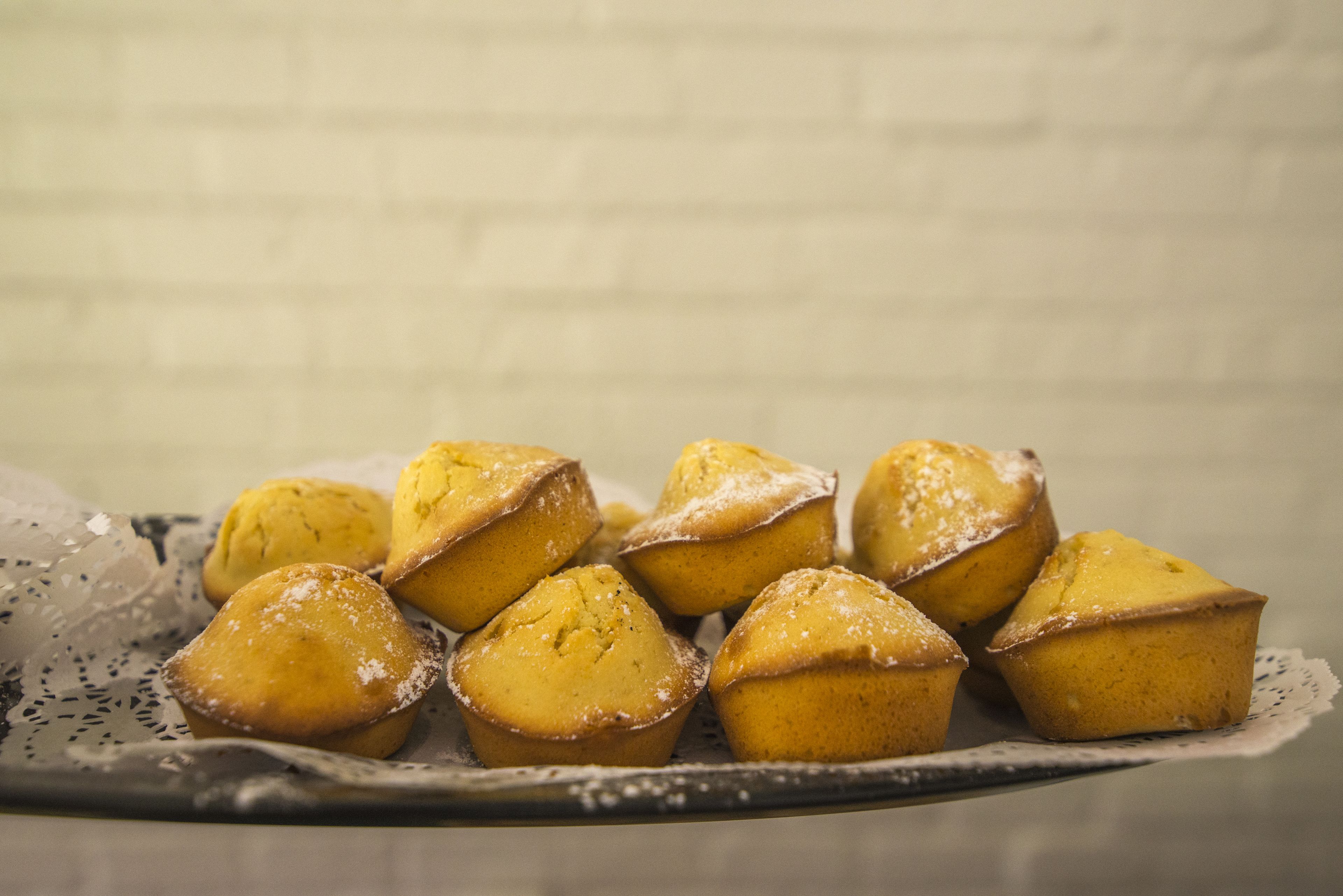 Una bandeja de muffins espolvoreados con azúcar glas sobre un encaje.