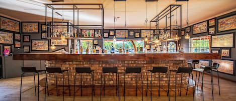 A bar area with a brick counter, multiple stools, and hanging light fixtures.