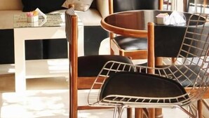 A cozy seating area with a wooden wall, a round table, and metal chairs. - Aguada Hotel (Trelew)