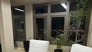 A modern office space with two white cushioned chairs, a round wooden table, and a potted plant. - Aguada Hotel (Trelew)