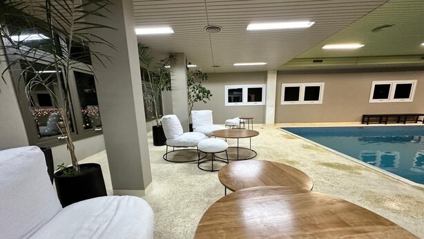 A poolside area with a pool, lounge chairs, and a wooden deck. - Aguada Hotel (Trelew)