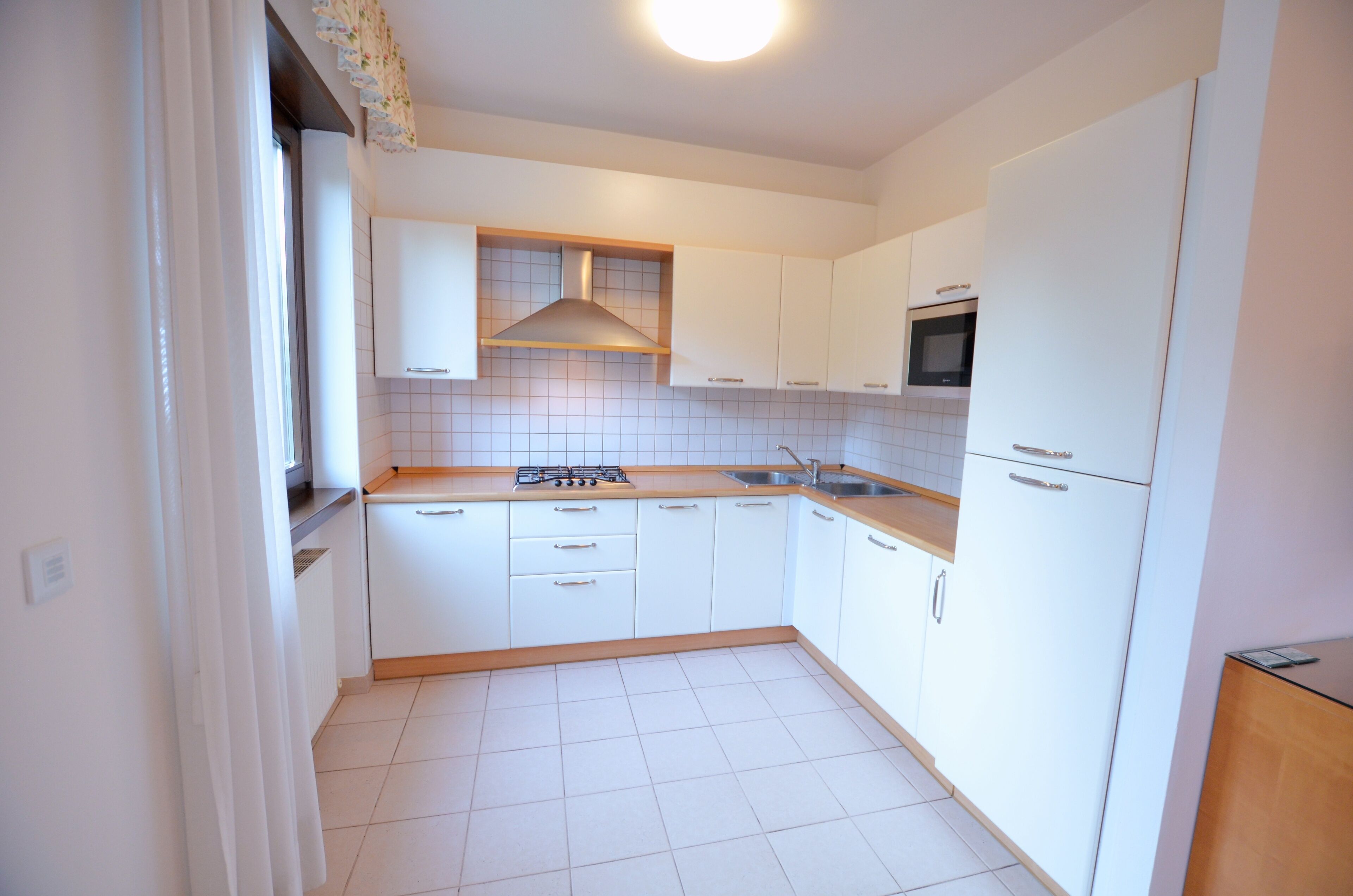 A compact kitchen with white cabinets, a gas stove, a microwave, and a sink.