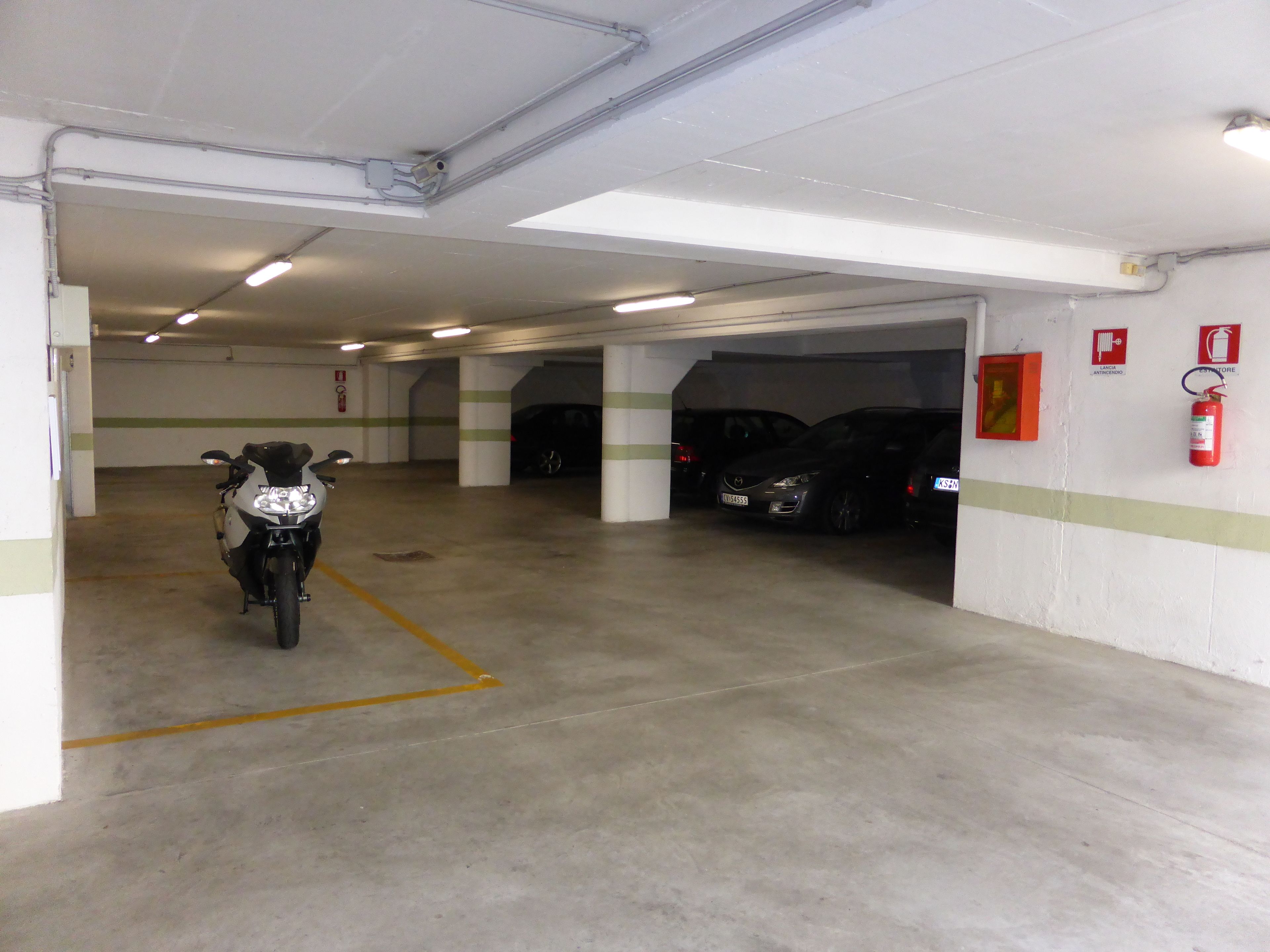 A multi-level parking garage with a motorcycle parked in the foreground and several cars parked in the background.