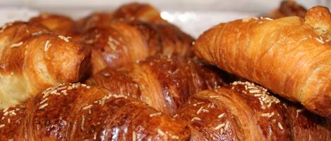 A tray of golden-brown croissants with sesame seeds, arranged on a white plate.