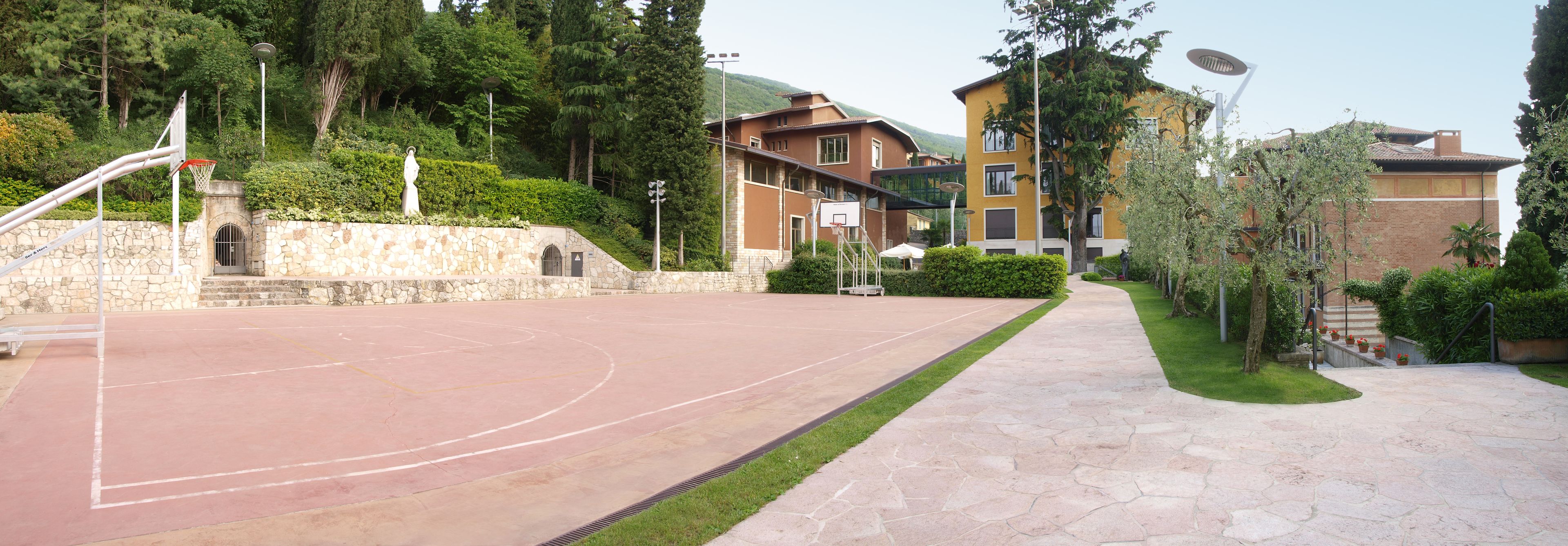 Un terrain de basket en plein air, doté d’un mur en pierre et d’un panier de basket.