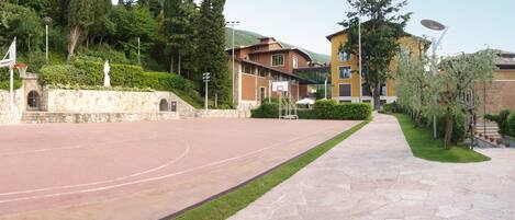 Un terrain de basket en plein air, doté d’un mur en pierre et d’un panier de basket.