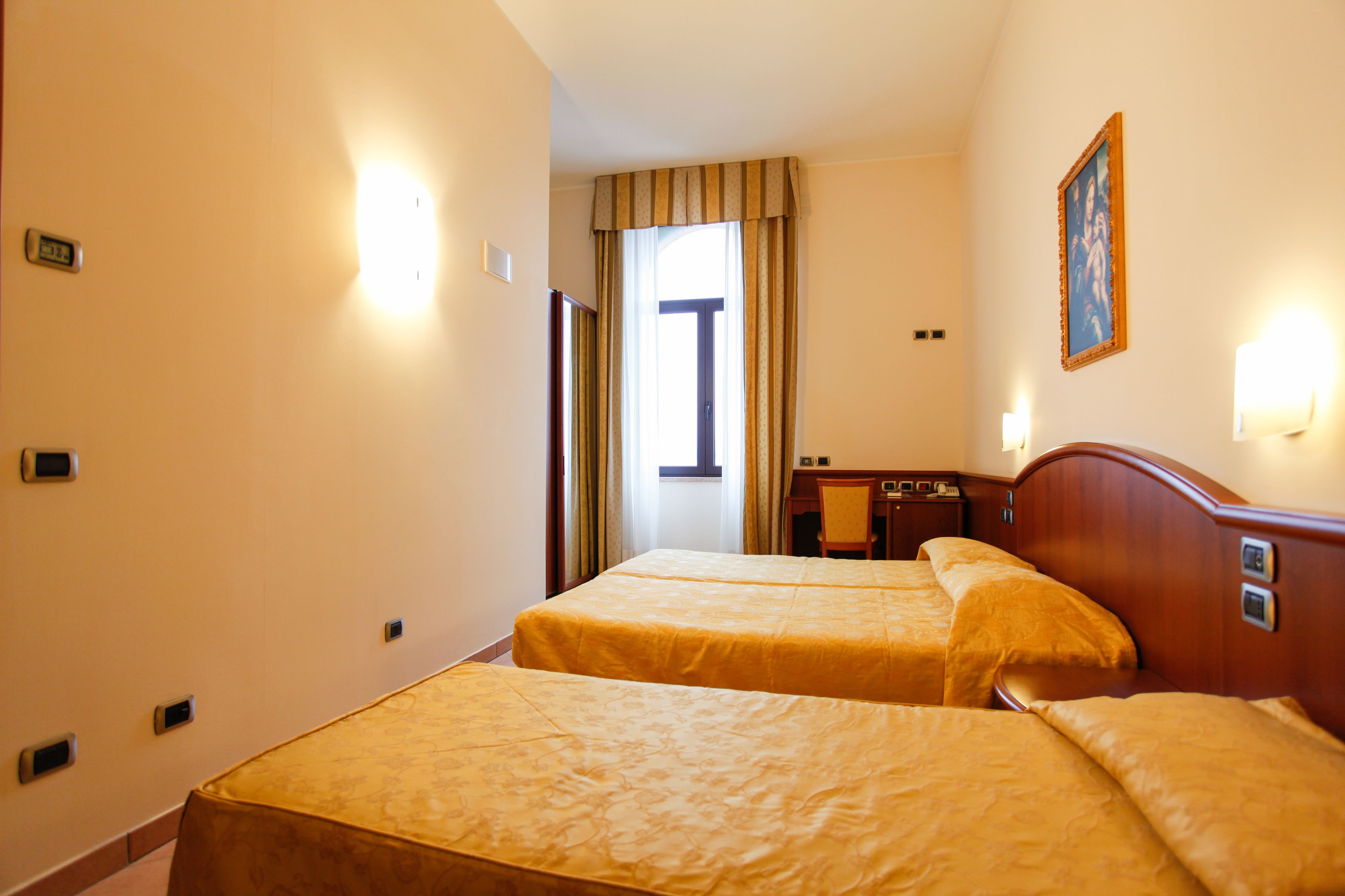 A hotel room with two beds, a desk, and a chair.