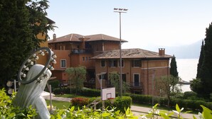 Un edificio con patio, cancha de baloncesto y vista al mar.