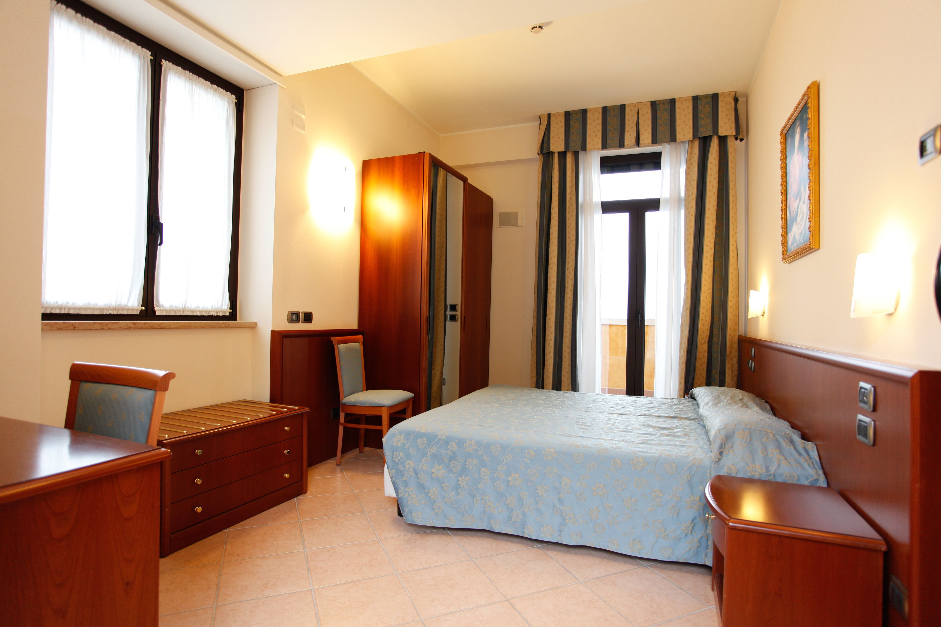 Une chambre à coucher comprenant un lit, un bureau, une chaise et une armoire.