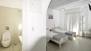 A modern hotel room with a shower, two beds, a small table, and a window with curtains.