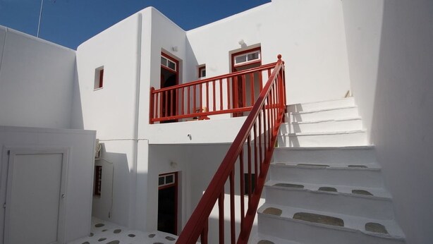 A white building with a red staircase and a door.