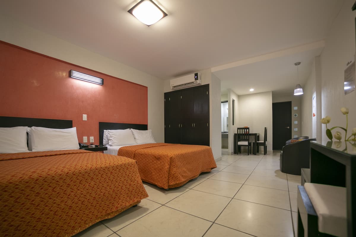 A hotel room with two beds, a desk, a chair, and a wardrobe.