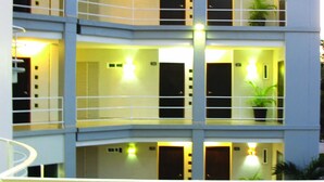 Um hotel com vários andares, varandas, piscina e área de estar ao ar livre.