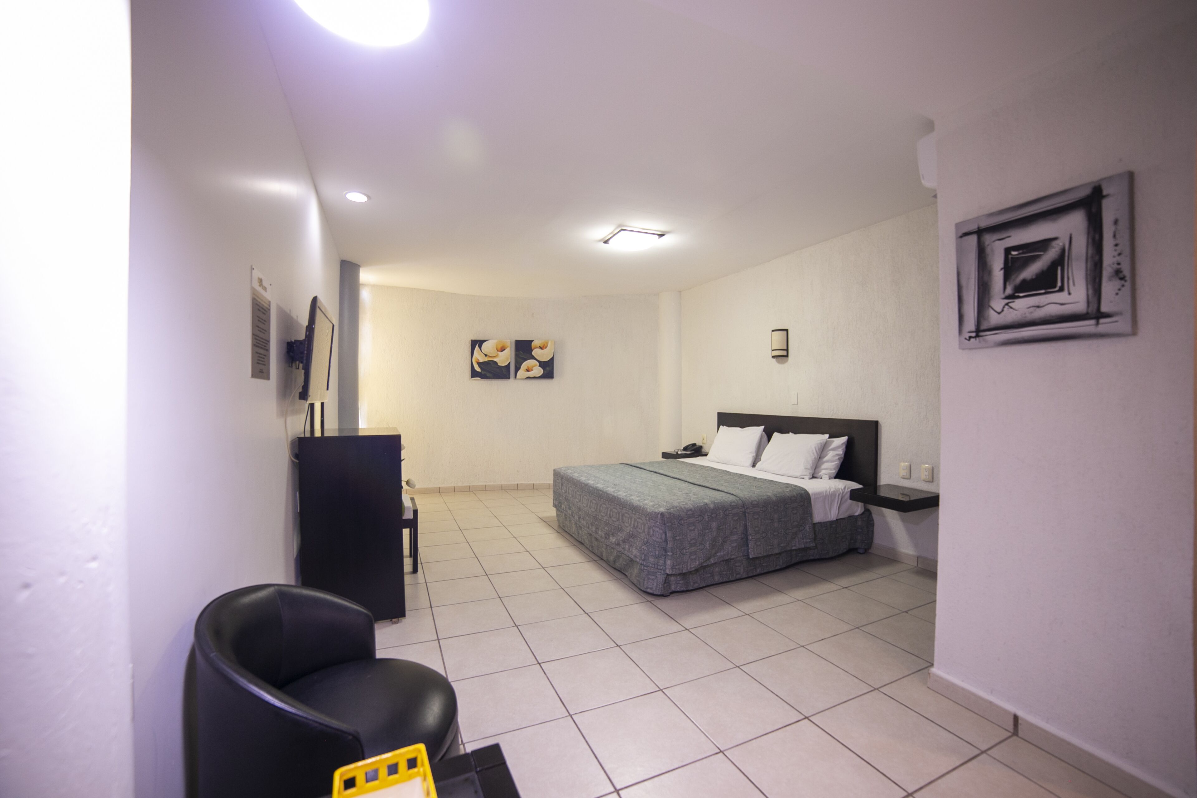 Une chambre d’hôtel avec un lit, un bureau, une chaise et une petite table.