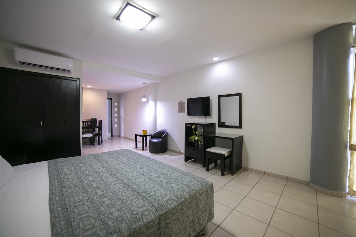 A hotel room with a bed, a desk, a chair, a TV, and a wardrobe.