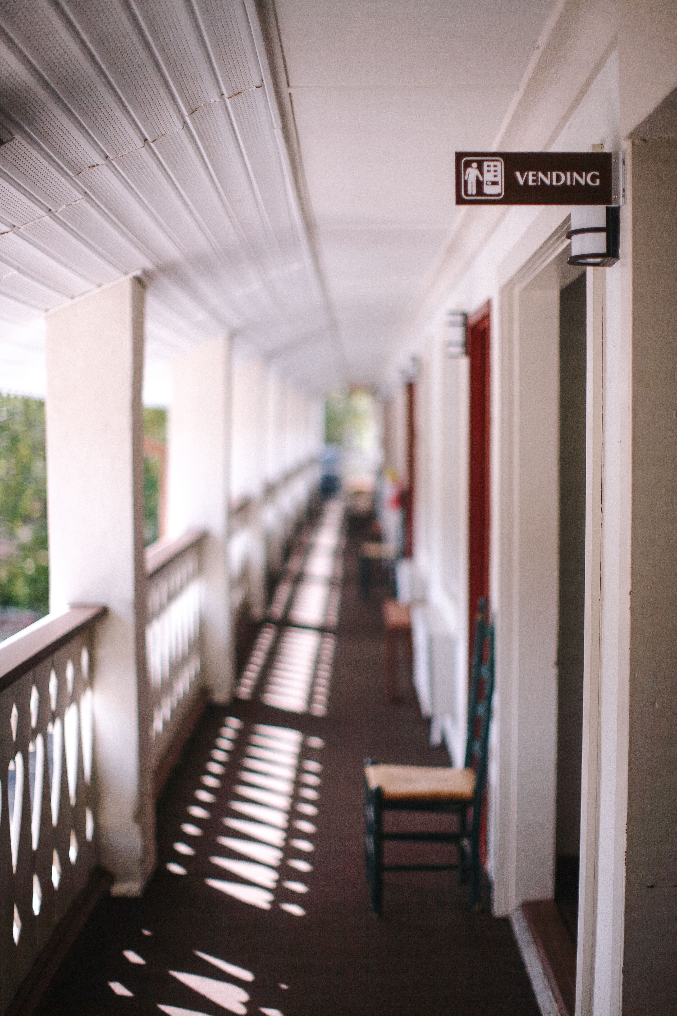 A corridor with a vending machine sign, a chair, and a door.