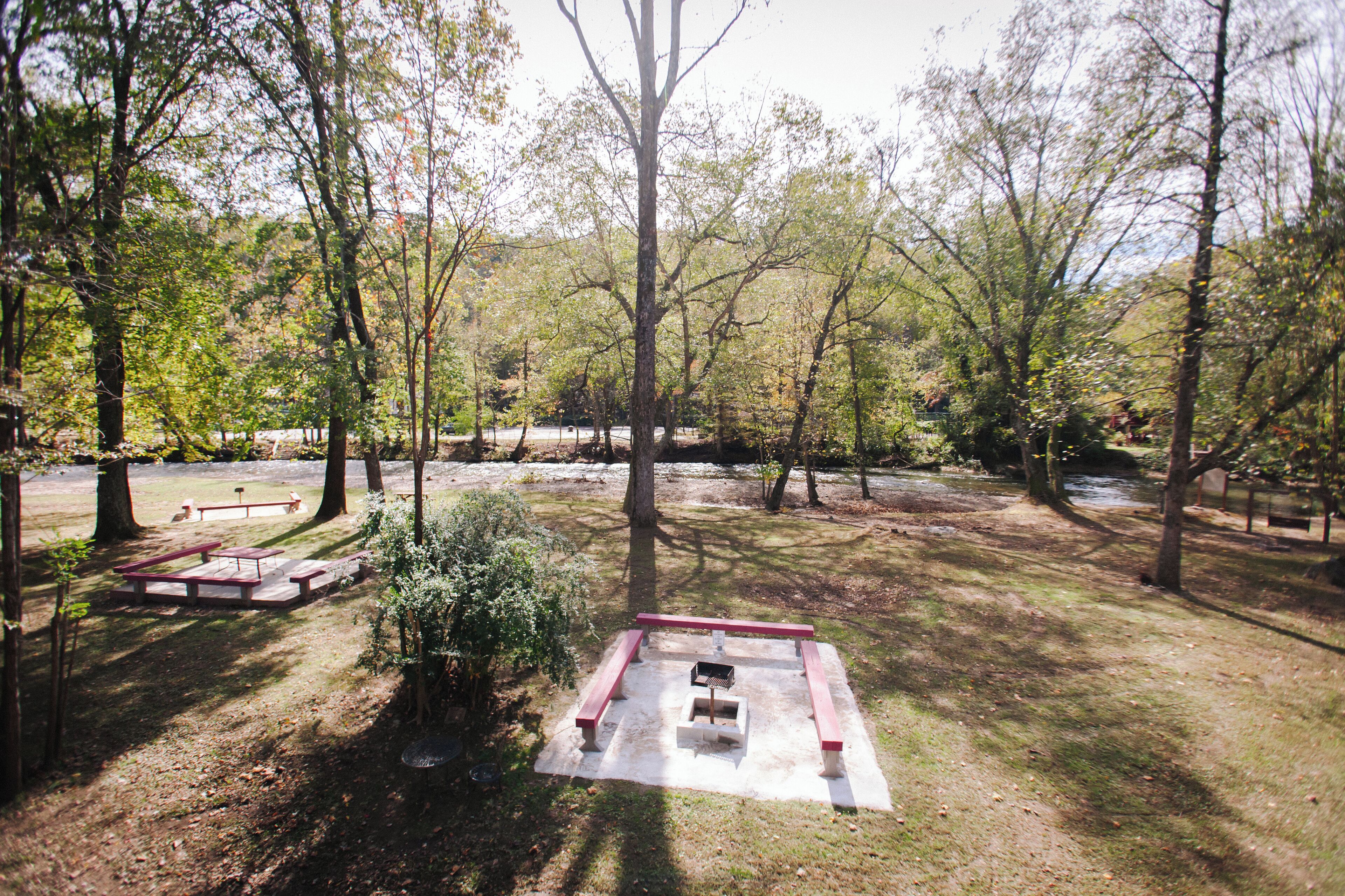 A picnic area with benches and a table, surrounded by trees.