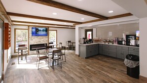 A spacious kitchen with wooden floors, a dining area with chairs, and a large TV on the wall. - Riverbend Motel & Cabins (Helen)
