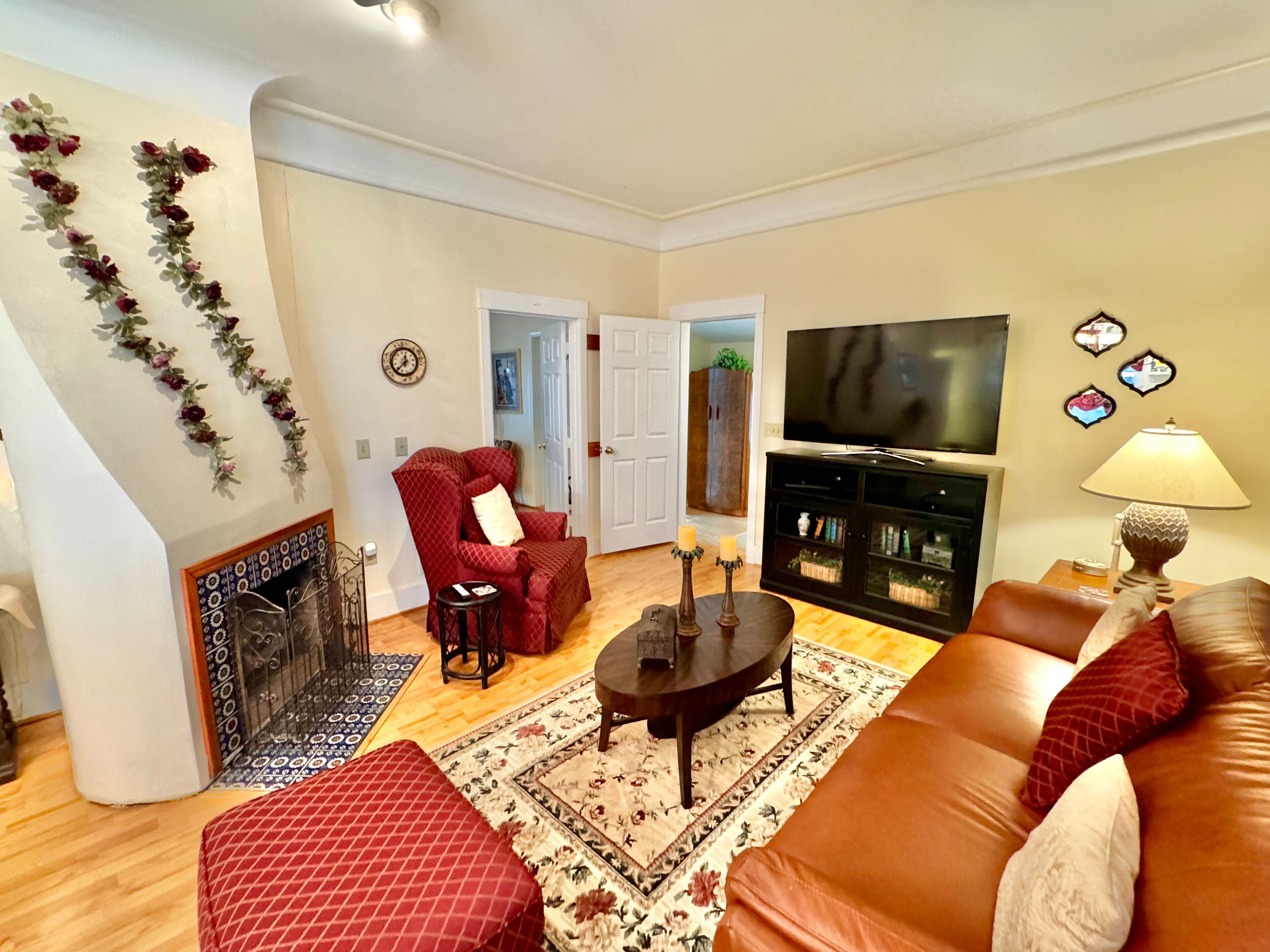 Una sala de estar con un sillón rojo, un sofá, un televisor, una chimenea y una guirnalda decorativa.