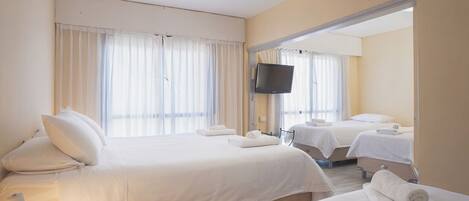 A hotel room with two beds, a flat-screen TV, and a large mirror.