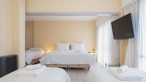 A hotel room with two beds, a flat-screen TV, and a window with curtains.