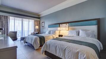 A hotel room with two beds, a desk, and a chair.