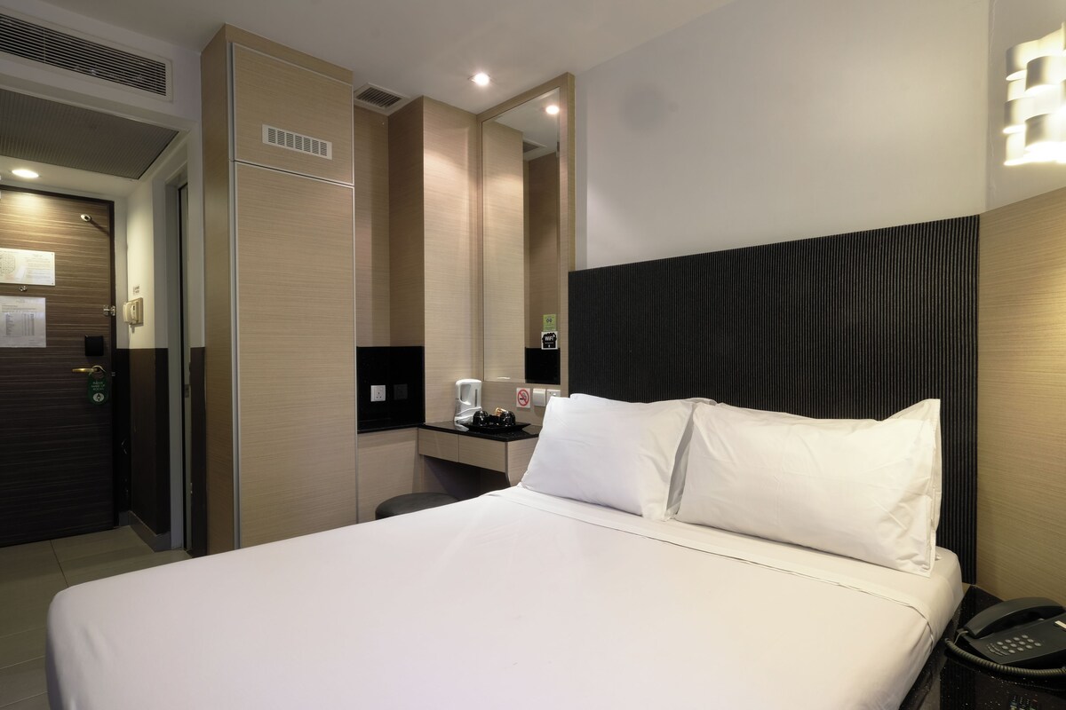 A hotel room with a bed, bedside table, and a phone.