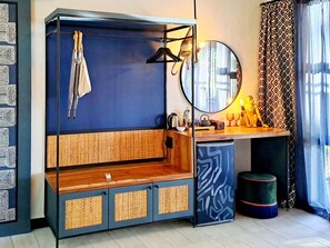 Une pièce comprenant un lit, un bureau en bois, un miroir et un petit tabouret.