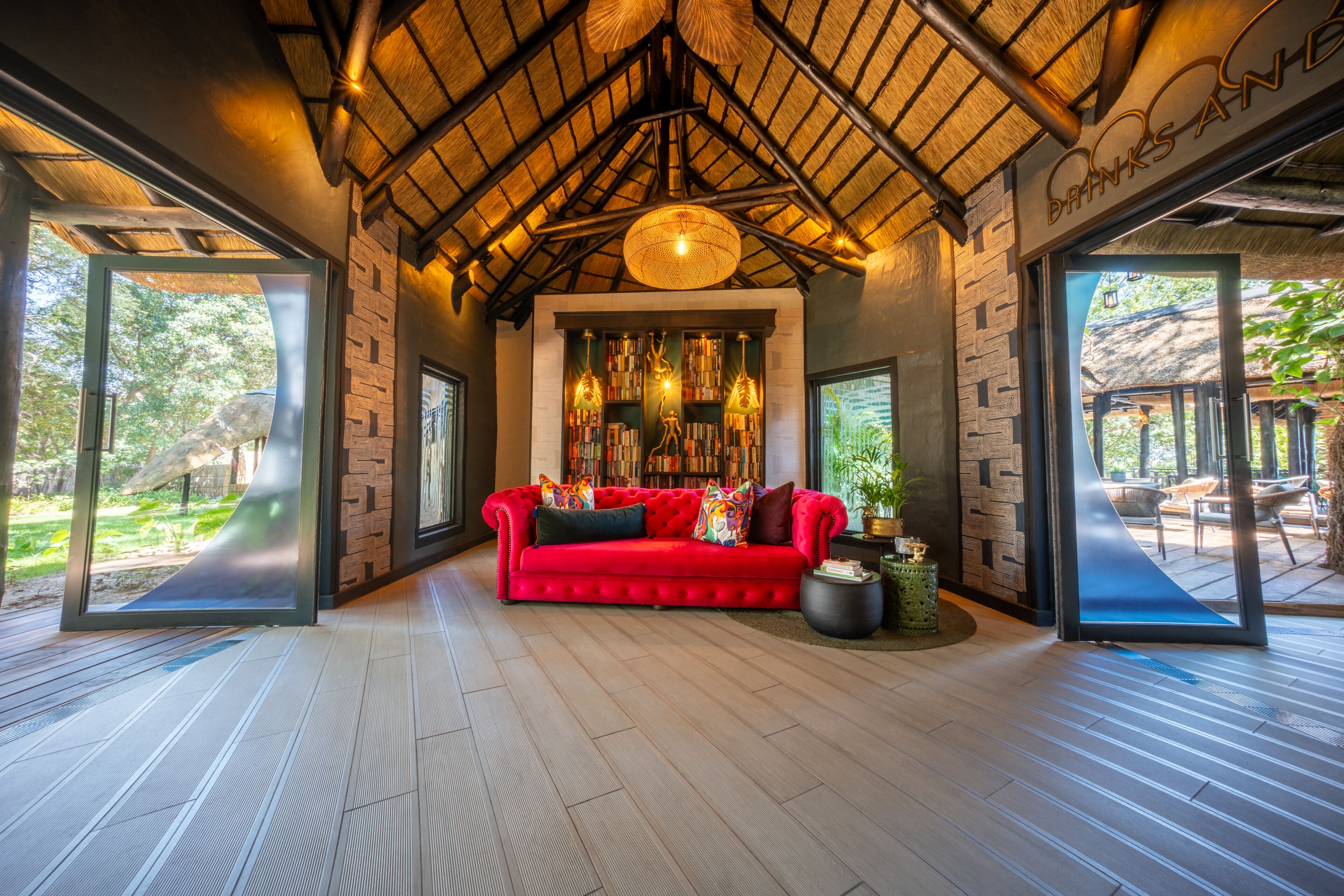 A modern interior with a red sofa, bookshelves, and a thatched ceiling.