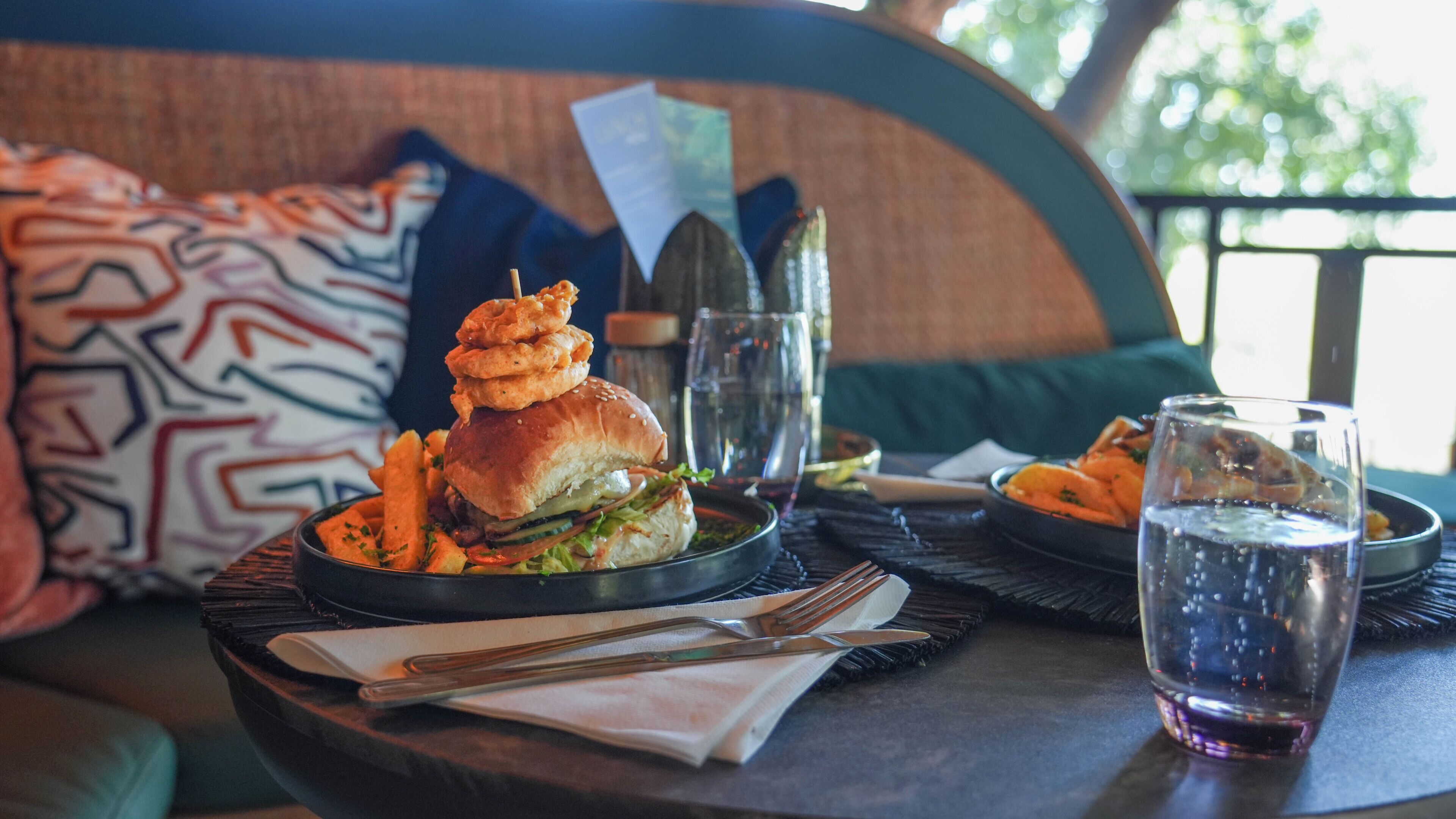 Une table à manger avec un hamburger, des frites et un verre d’eau.