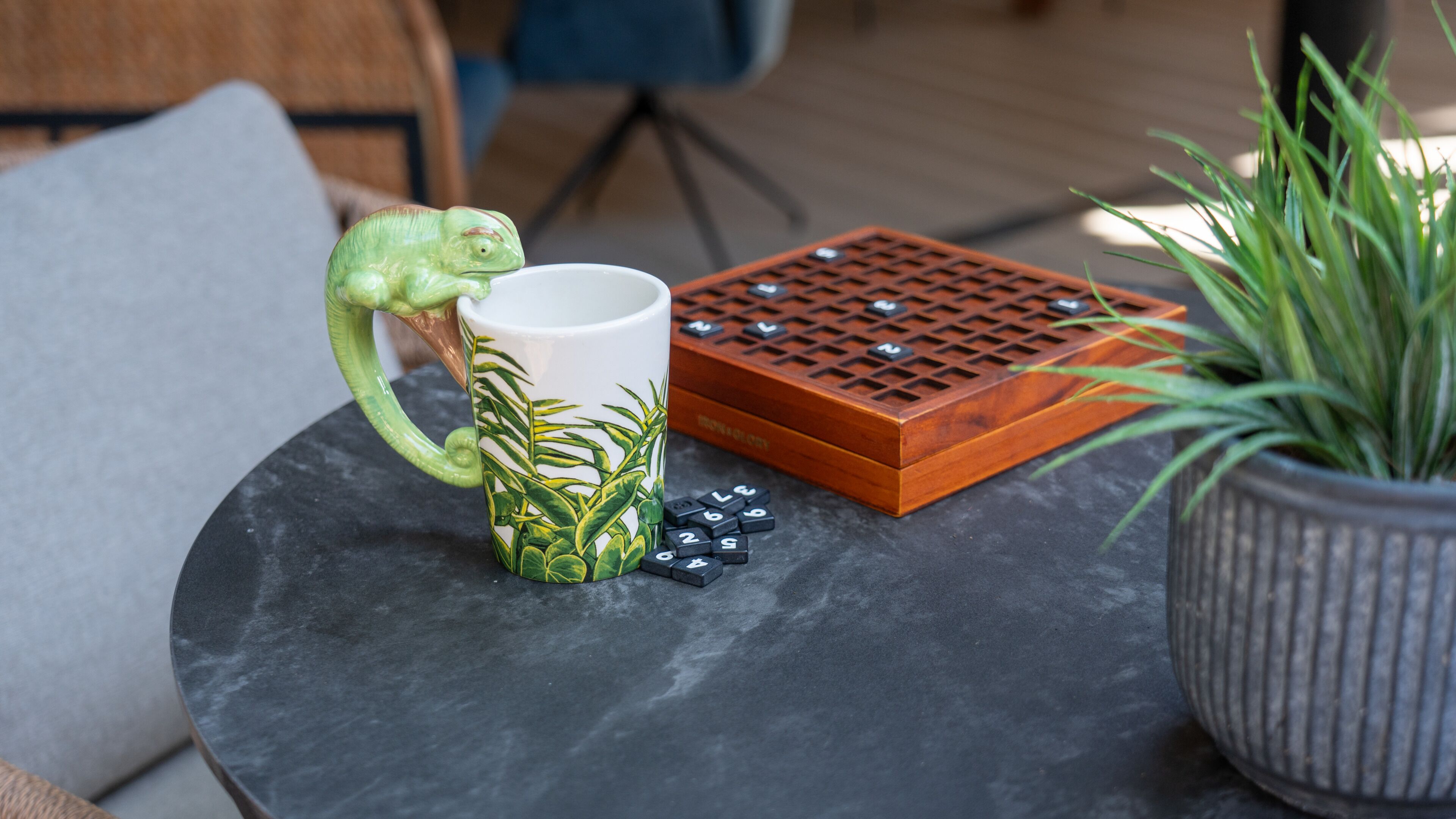 A table with a ceramic mug, a wooden puzzle, and a potted plant.