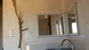 A bathroom with a rustic design, featuring a wooden branch decoration, a large mirror, and a black sink.