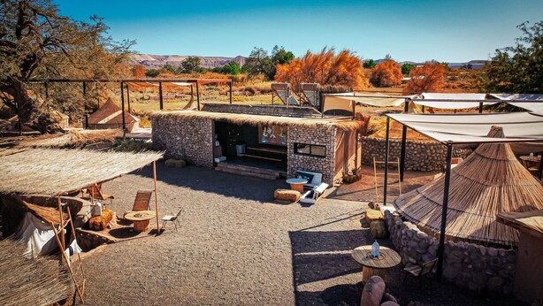 Un espacio al aire libre rústico con estructuras de piedra, techos de paja y zonas de estar.
