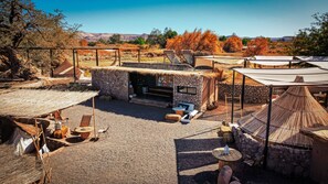 Un espacio al aire libre rústico con estructuras de piedra, techos de paja y zonas de estar.