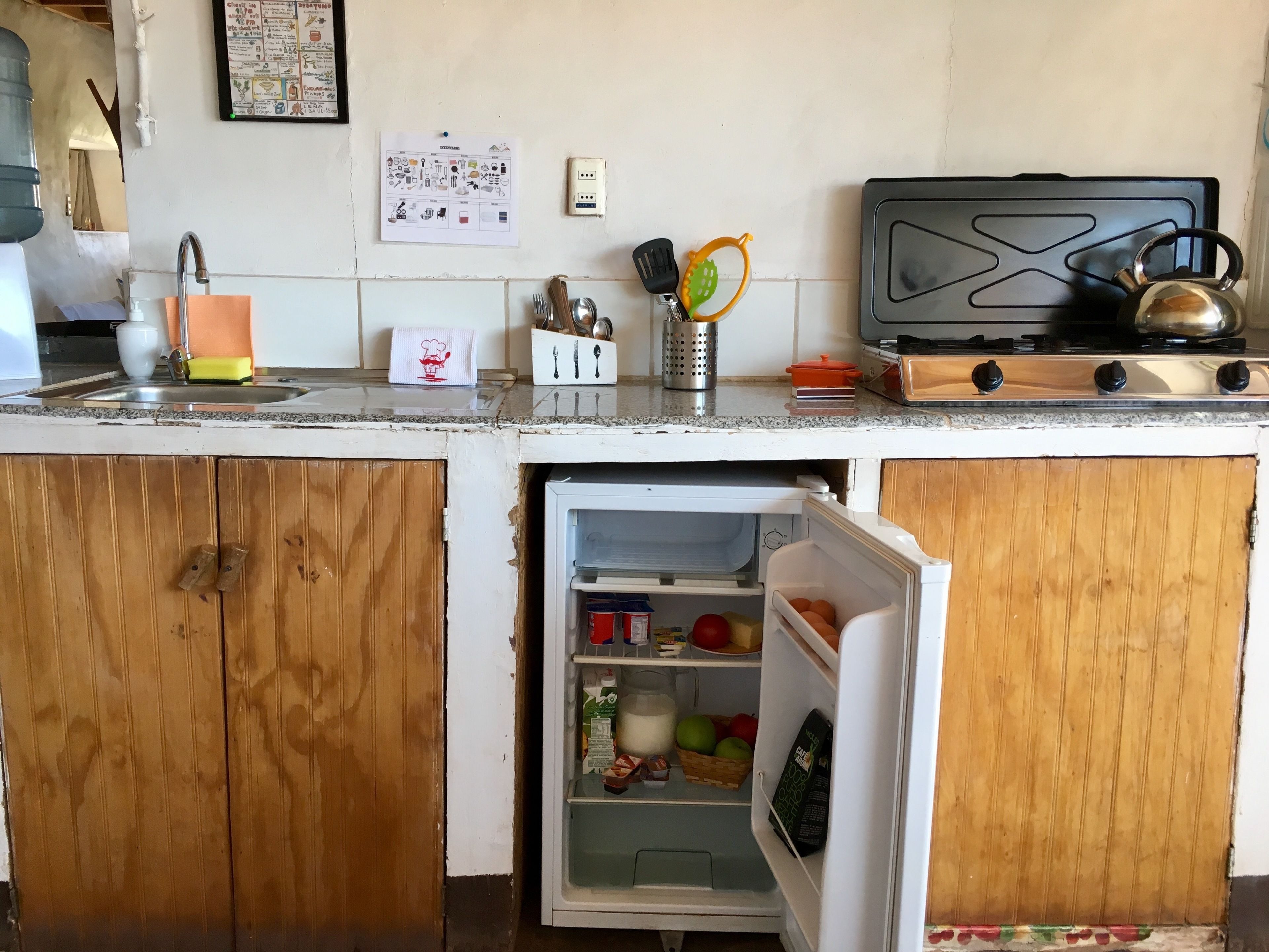 Una cocina con un refrigerador, una estufa y diversos utensilios de cocina.