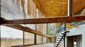 Un amplio salón con un ventanal grande, una escalera y un sofá.
