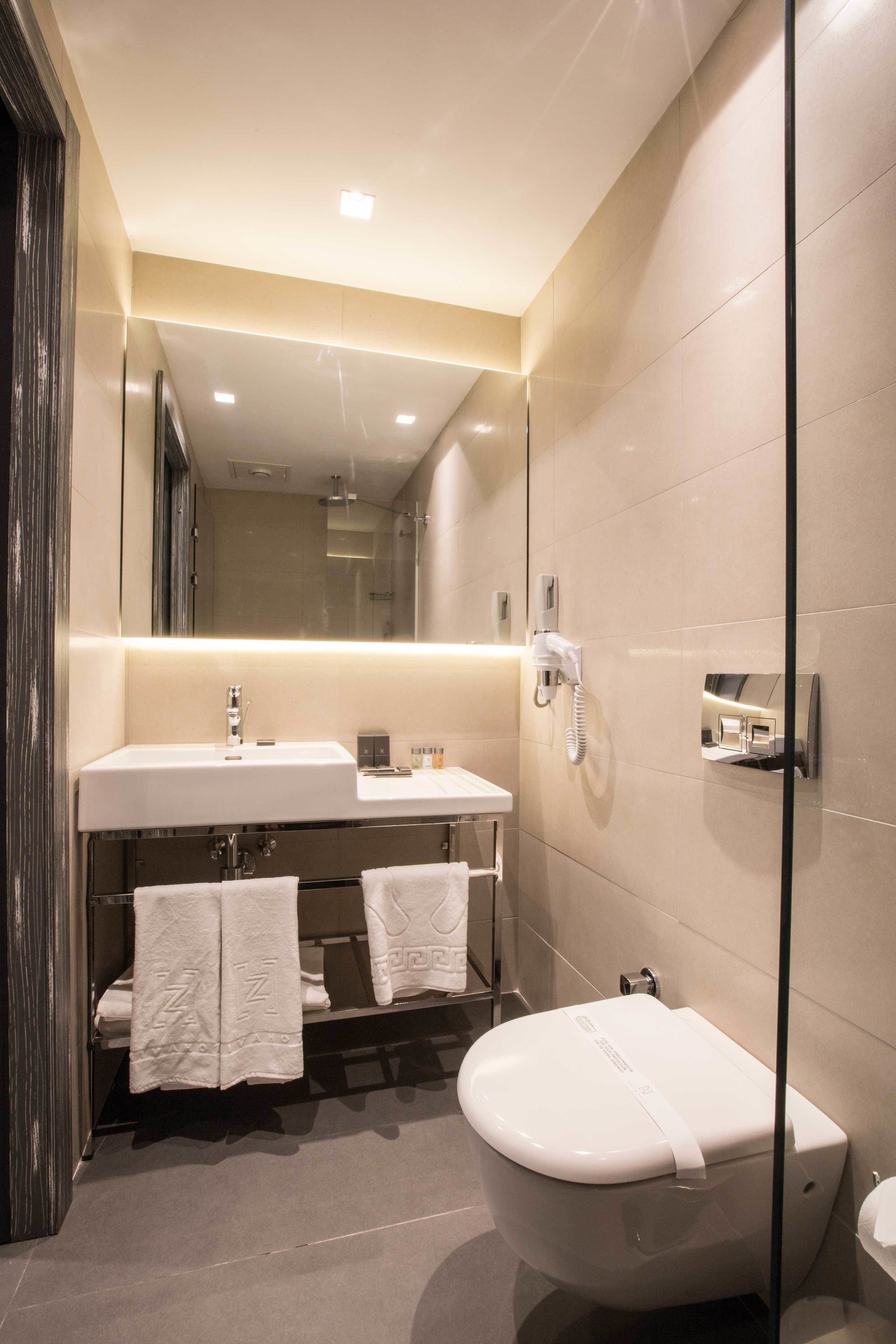 A modern bathroom with a large mirror, a sink, and a toilet.