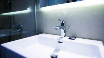 A modern bathroom with a white sink, chrome faucet, and a mirror above it.