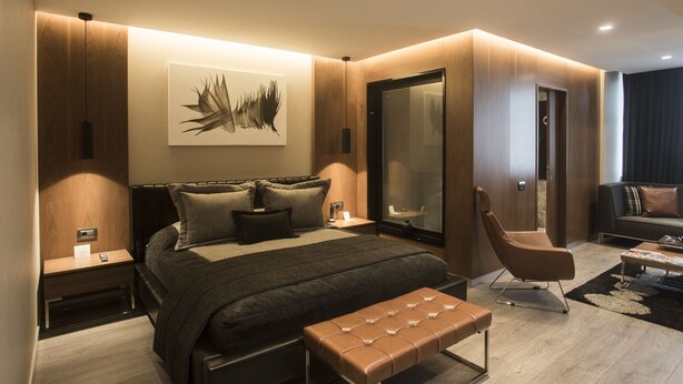 A modern bedroom with a large bed, a bench, a chair, and a nightstand. - Zeniva Hotel (Izmir)