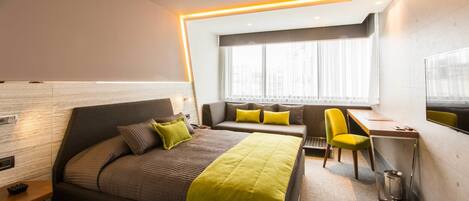 Une chambre d’hôtel moderne équipée d’un lit, d’un bureau, d’une chaise et d’une fenêtre avec des rideaux.